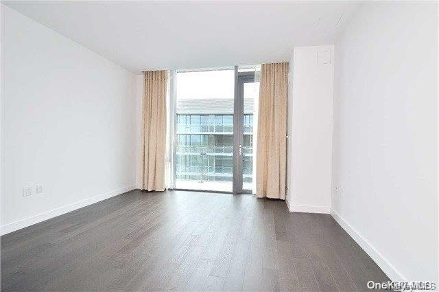 spare room featuring expansive windows and dark hardwood / wood-style floors