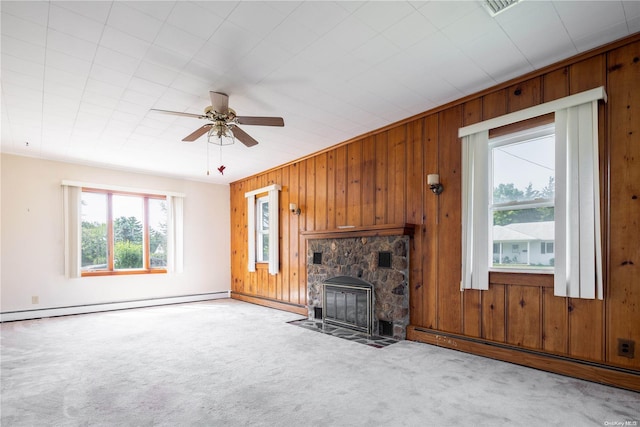 unfurnished living room with a fireplace, light carpet, baseboard heating, and wooden walls