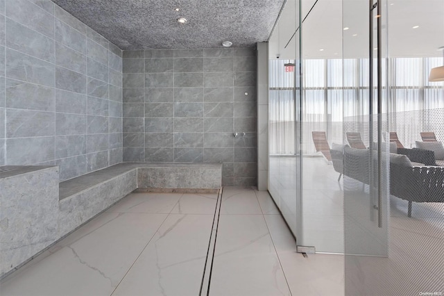 hallway with a wall of windows, tile walls, and a wealth of natural light