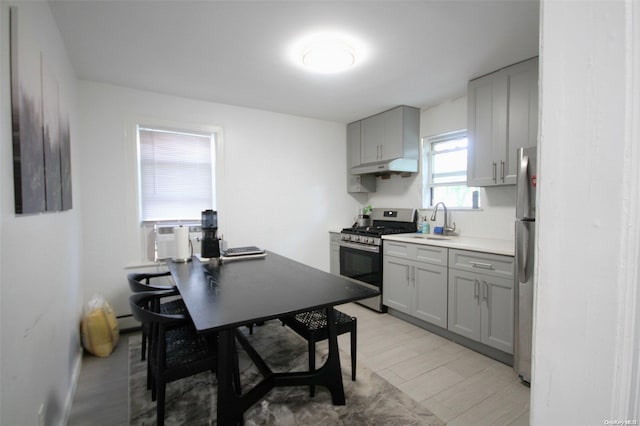 kitchen with gray cabinetry, sink, a baseboard heating unit, cooling unit, and appliances with stainless steel finishes