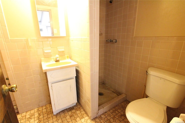 bathroom with tiled shower, vanity, and tile walls