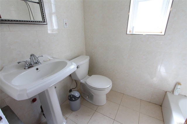 bathroom featuring sink, tile patterned floors, a tub to relax in, toilet, and tile walls