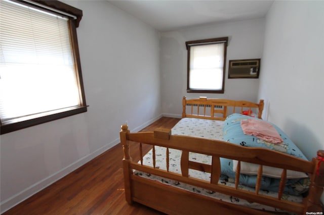 bedroom featuring a wall mounted AC and dark wood-type flooring