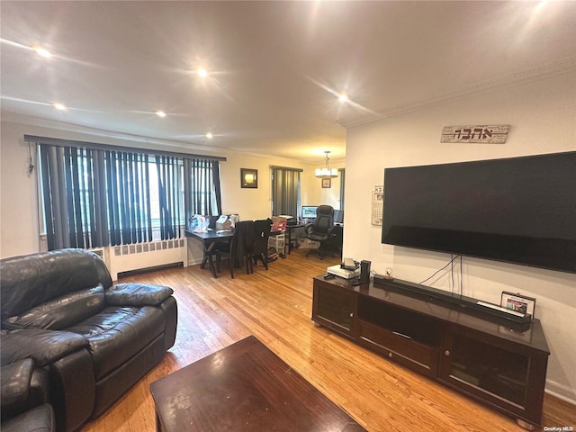 living room featuring hardwood / wood-style floors, a notable chandelier, radiator heating unit, and crown molding