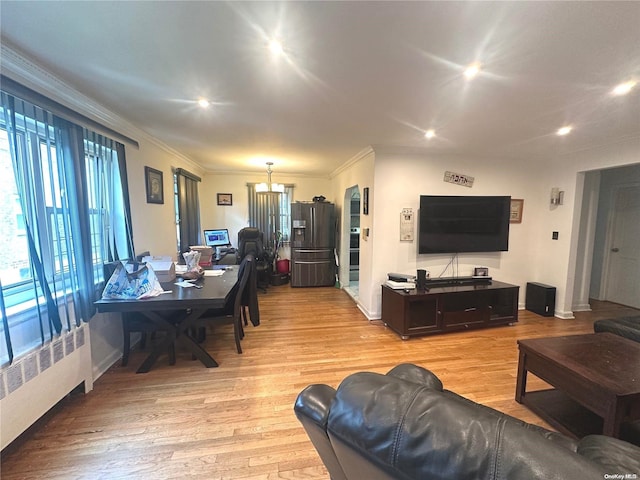 living room with a wealth of natural light, radiator heating unit, crown molding, and light wood-type flooring