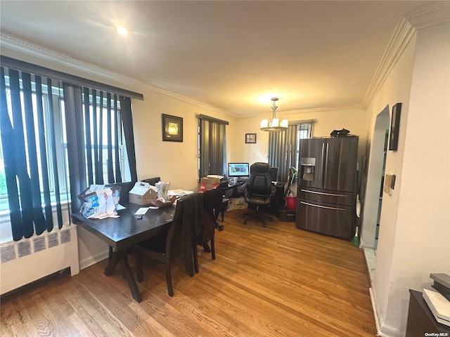 dining space with hardwood / wood-style floors, radiator, ornamental molding, and a notable chandelier