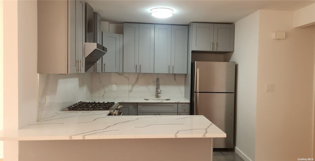 kitchen with appliances with stainless steel finishes, gray cabinets, light stone counters, and sink