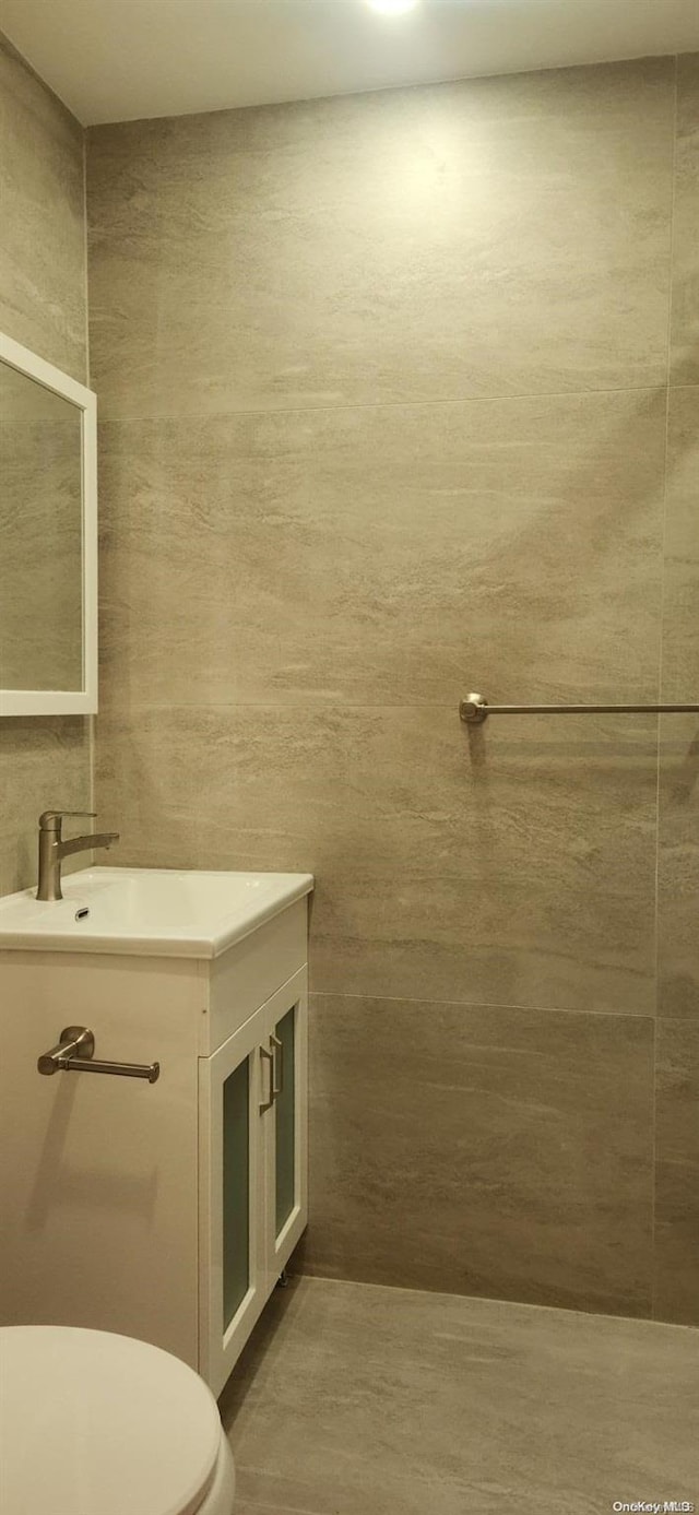 bathroom featuring vanity, toilet, and tile walls