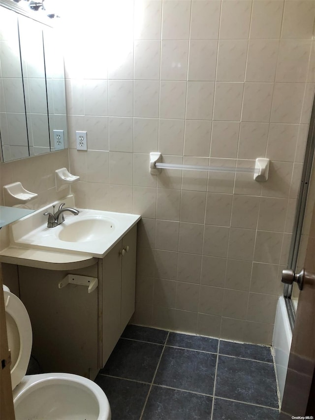 full bathroom with tile patterned flooring, toilet, shower / bath combination with glass door, vanity, and tile walls