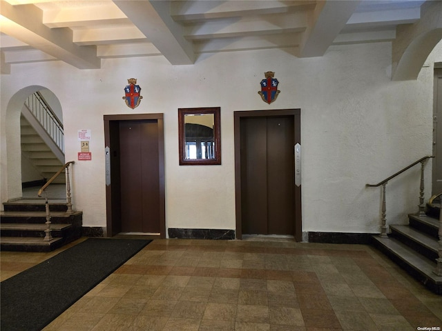 entryway with beam ceiling, elevator, and a towering ceiling