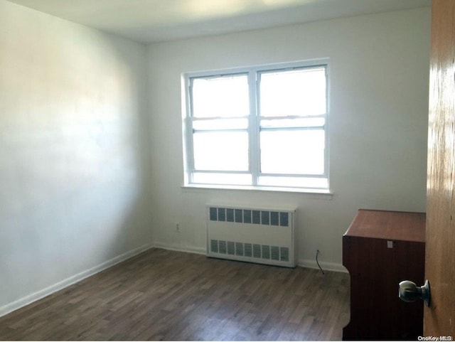 empty room with dark wood-type flooring and radiator