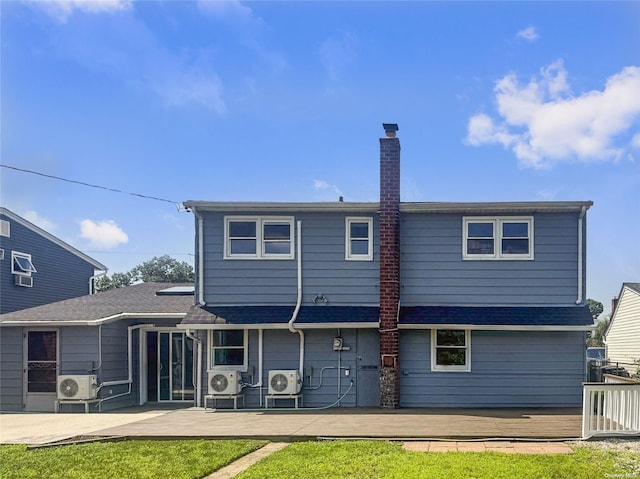 rear view of house with ac unit, a lawn, and a wooden deck