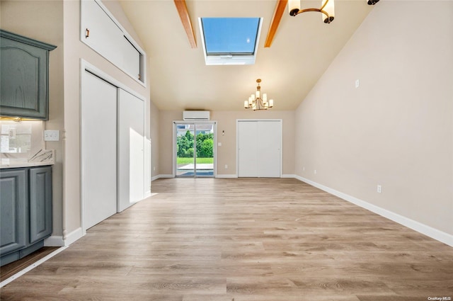 interior space featuring light wood-type flooring, a skylight, a wall mounted AC, high vaulted ceiling, and beamed ceiling