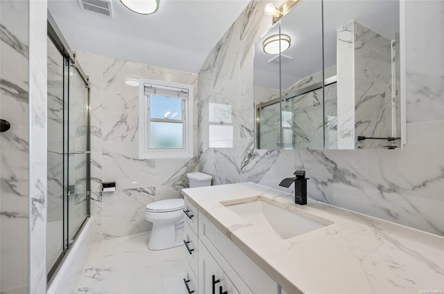 full bathroom featuring vanity, toilet, tile walls, and bath / shower combo with glass door