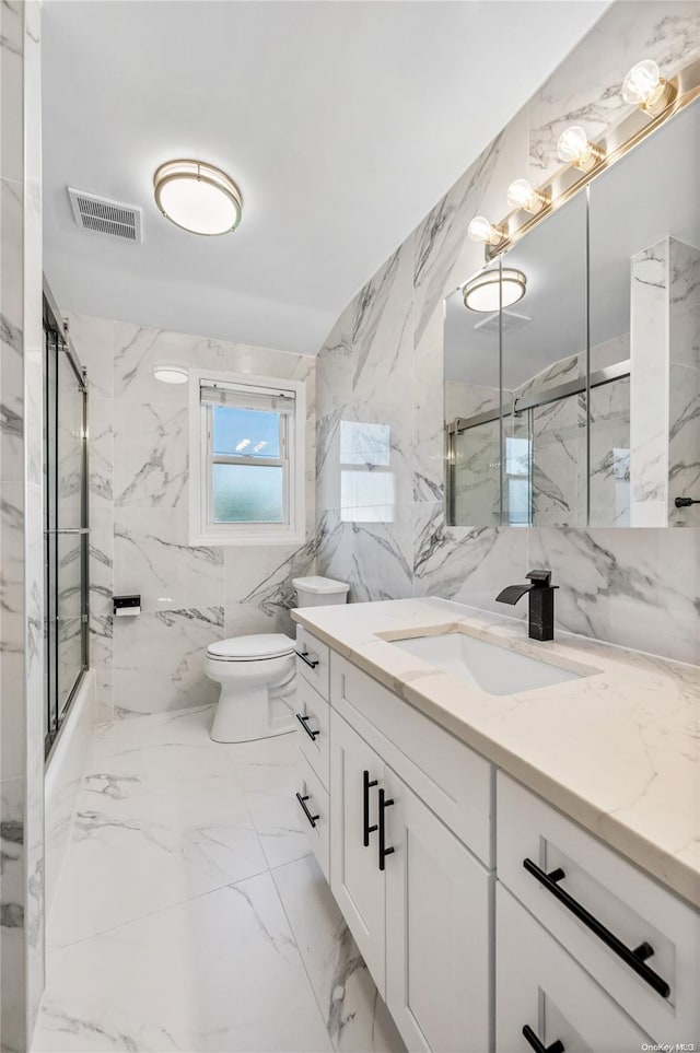 full bathroom with vanity, toilet, tile walls, and bath / shower combo with glass door