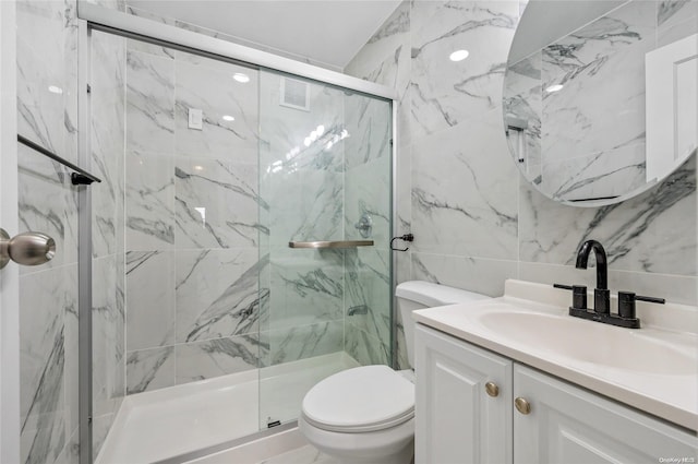 bathroom with vanity, toilet, a shower with door, and tile walls