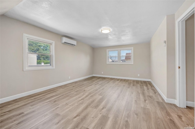 spare room featuring a wall mounted air conditioner and light hardwood / wood-style flooring