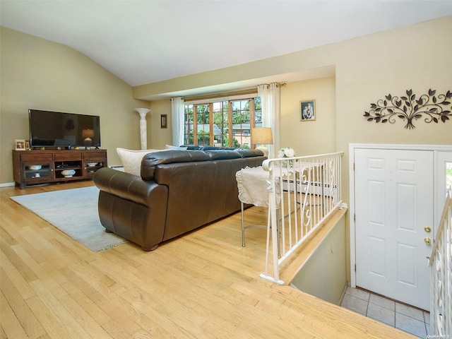 living room with ornate columns, light hardwood / wood-style floors, vaulted ceiling, and a baseboard heating unit