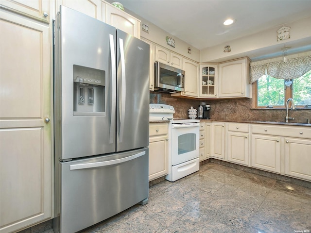 kitchen with cream cabinetry, stainless steel appliances, tasteful backsplash, and sink