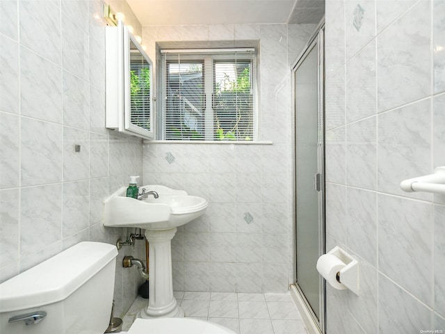 bathroom with a shower with shower door, tile walls, and toilet