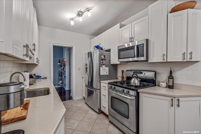 kitchen featuring white cabinets, appliances with stainless steel finishes, light tile patterned floors, and sink