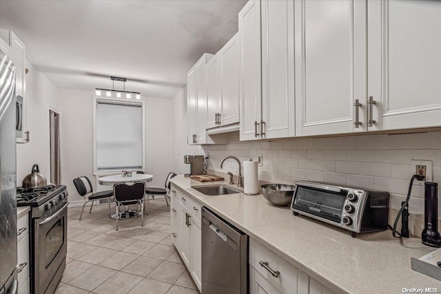 kitchen with white cabinets, sink, light tile patterned floors, appliances with stainless steel finishes, and tasteful backsplash