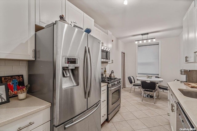 kitchen featuring white cabinets, stainless steel appliances, and light tile patterned flooring