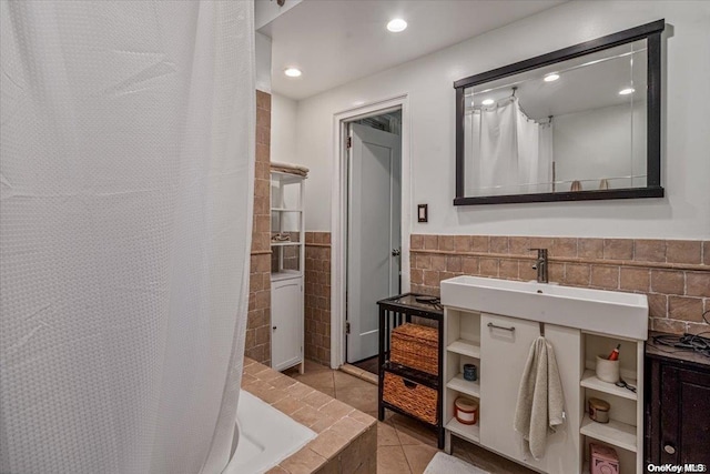 bathroom featuring tile patterned flooring, curtained shower, sink, and tile walls