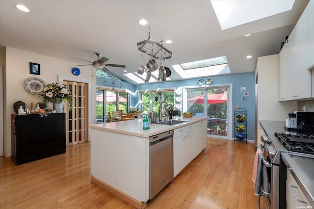 kitchen with white cabinetry, sink, stainless steel appliances, light hardwood / wood-style flooring, and a kitchen island with sink