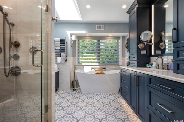 bathroom featuring a skylight, vanity, and shower with separate bathtub