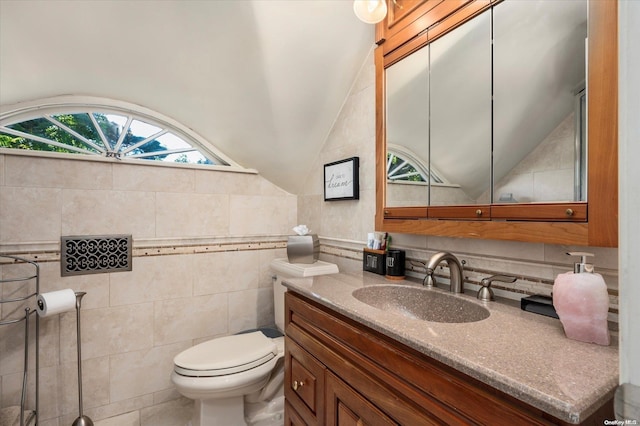 bathroom featuring vanity, toilet, tile walls, and lofted ceiling