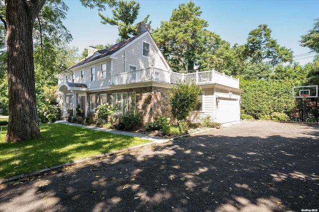 view of front facade featuring a balcony, a front yard, and a garage