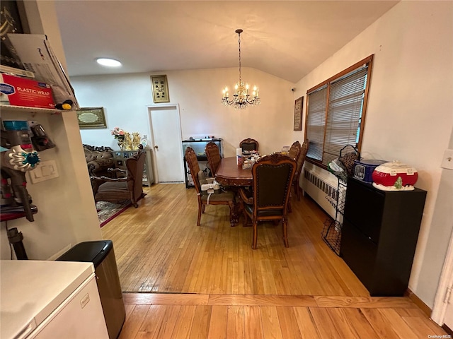 dining area featuring lofted ceiling, light hardwood / wood-style floors, radiator heating unit, and an inviting chandelier