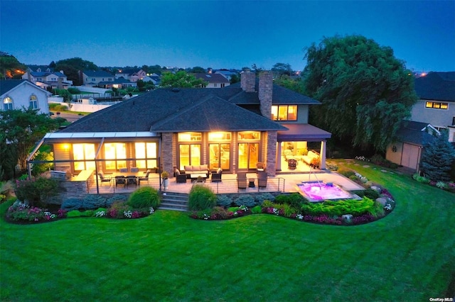 rear view of house with a patio area, an outdoor living space with a fireplace, a chimney, and a lawn