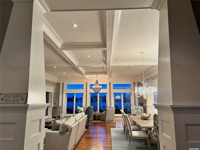 living room featuring coffered ceiling, wood finished floors, crown molding, a decorative wall, and a notable chandelier