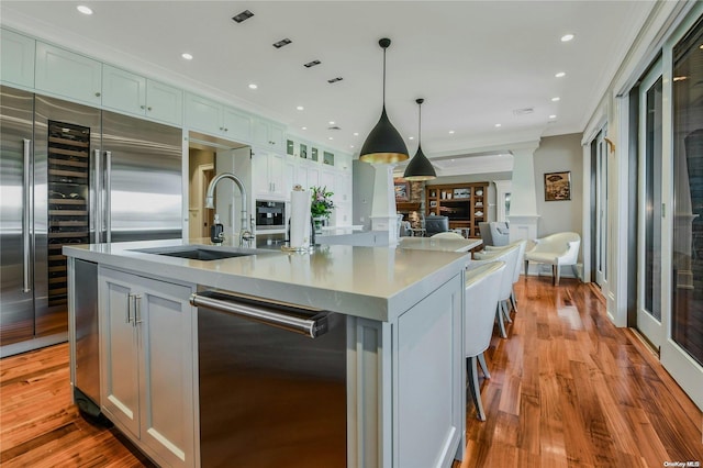 kitchen featuring decorative light fixtures, a spacious island, light countertops, light wood-style flooring, and a sink