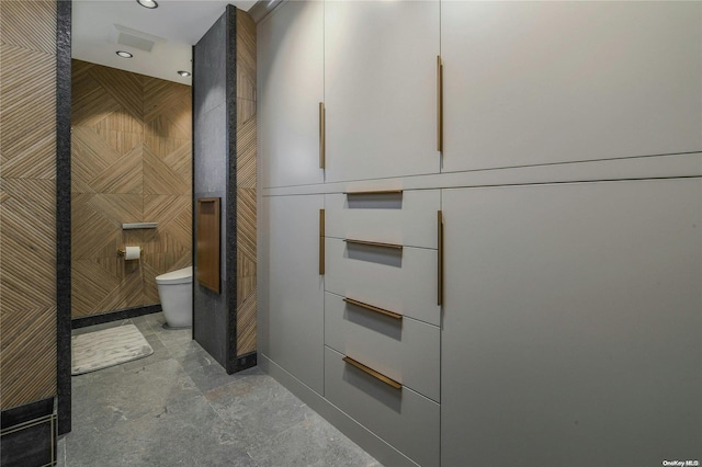 bathroom featuring toilet and tile walls