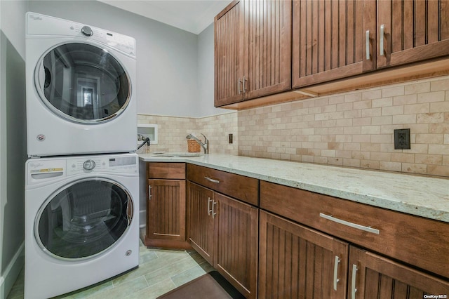 clothes washing area featuring a sink, cabinet space, and stacked washer / drying machine