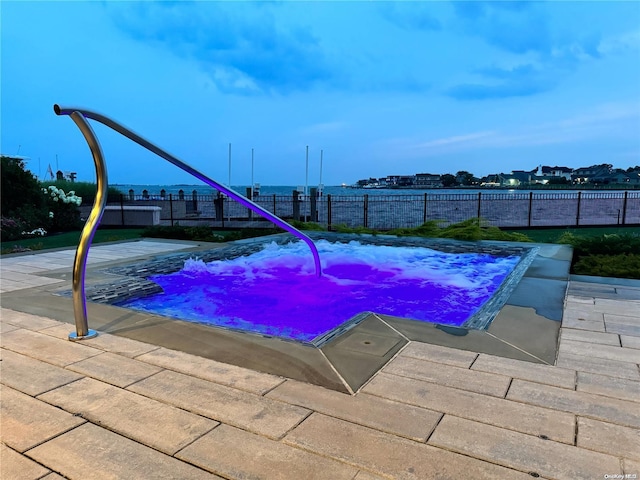 view of pool with fence and a hot tub