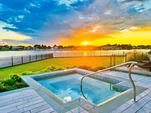 view of swimming pool featuring a water view, a yard, and a fenced backyard