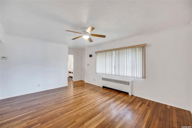 empty room with hardwood / wood-style floors, radiator, crown molding, and ceiling fan