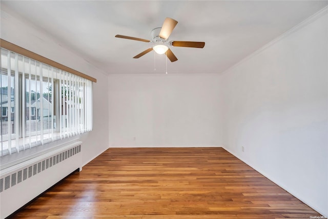 spare room featuring wood-type flooring, radiator, ornamental molding, and ceiling fan