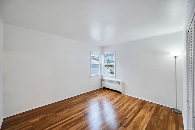 unfurnished room featuring radiator heating unit and wood-type flooring