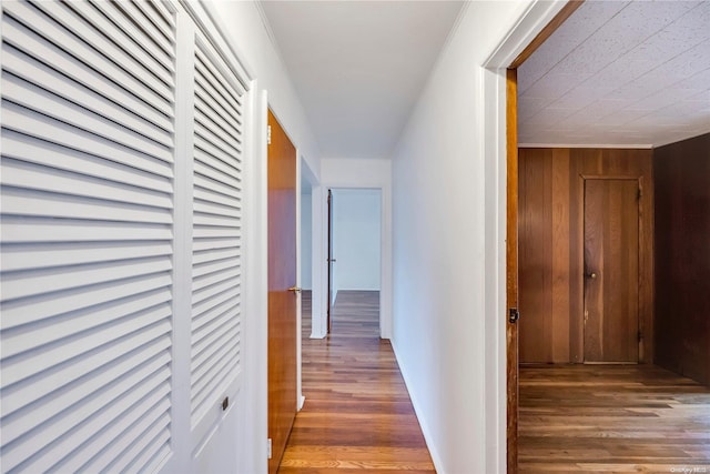 hallway featuring dark hardwood / wood-style floors, crown molding, and wooden walls