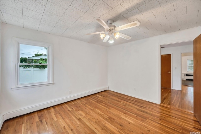 unfurnished room featuring light hardwood / wood-style flooring, ceiling fan, and a baseboard heating unit