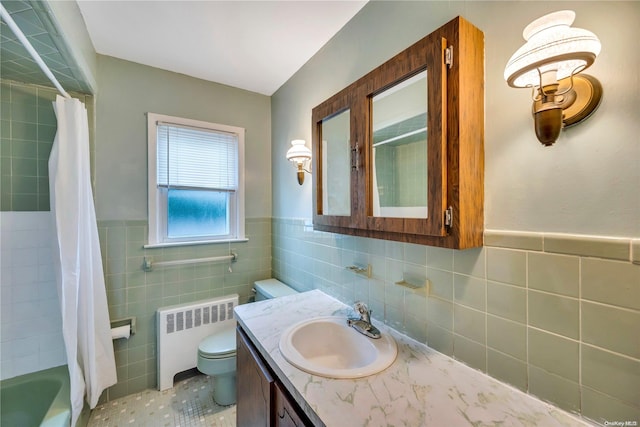 full bathroom featuring radiator, tile walls, toilet, vanity, and shower / tub combo