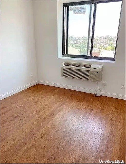 unfurnished room featuring hardwood / wood-style flooring and a wall unit AC