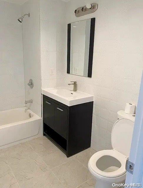 full bathroom featuring vanity, tiled shower / bath combo, tile walls, and toilet