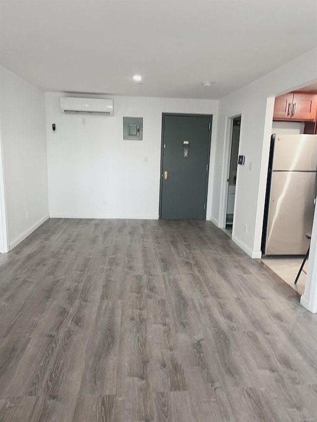 spare room with light hardwood / wood-style floors, an AC wall unit, and electric panel