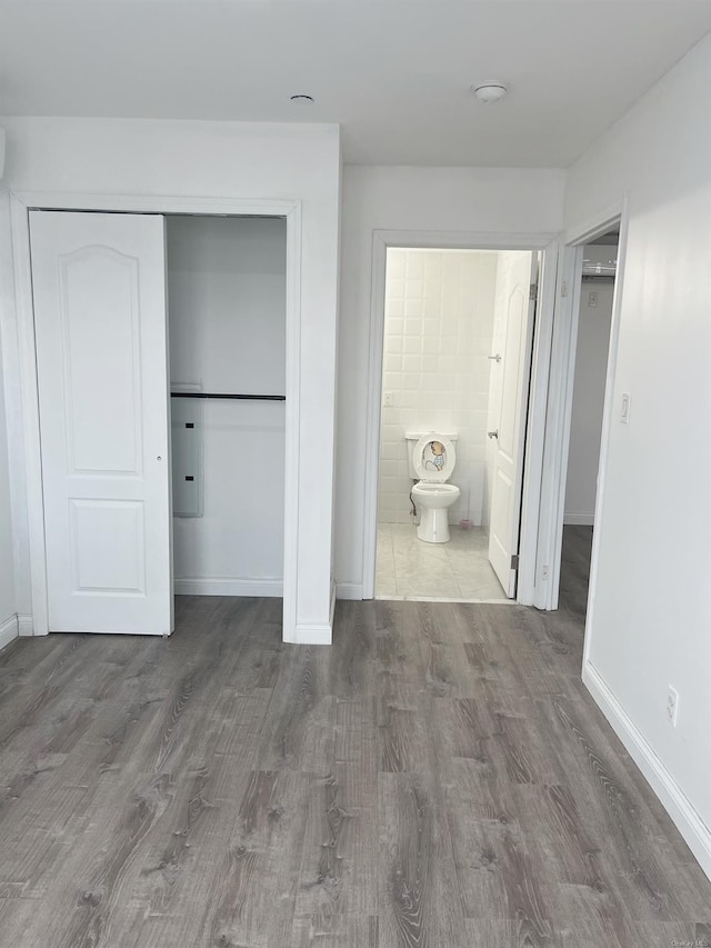 unfurnished bedroom with hardwood / wood-style flooring, connected bathroom, and a closet